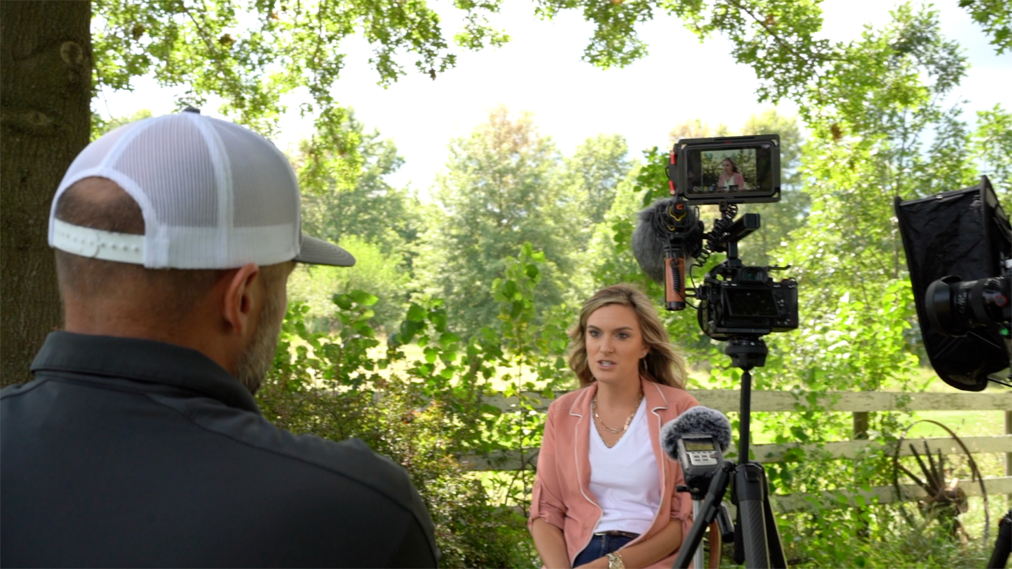 joe with hat on filming lady in peach jacket outside